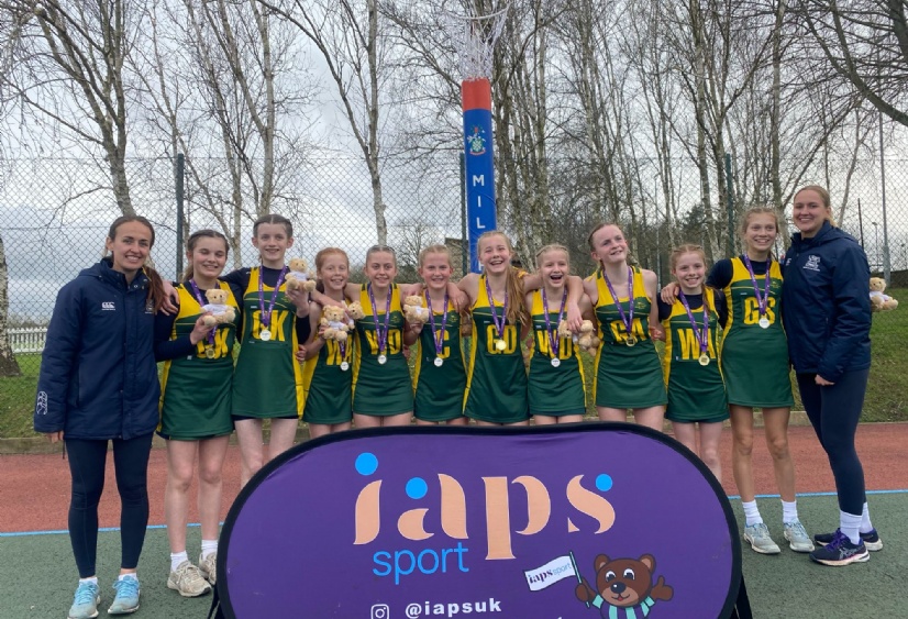 Heath Mount's U13 netballers stand with their gold medals alongside their coaches at Millfield School